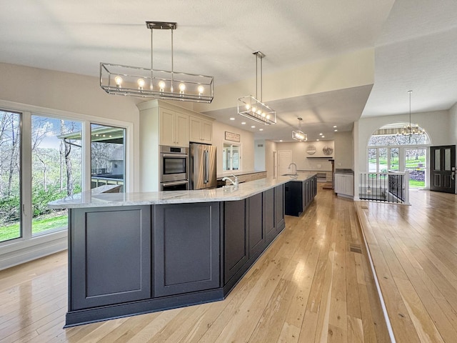 kitchen featuring a large island, stainless steel appliances, decorative light fixtures, and white cabinets