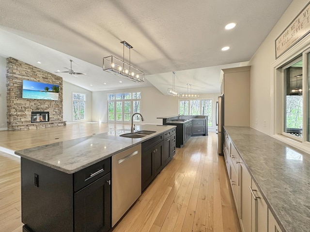 kitchen featuring pendant lighting, sink, stainless steel appliances, a spacious island, and a stone fireplace