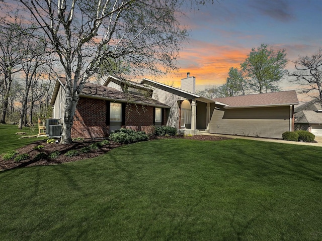 view of front of house with a yard and central AC