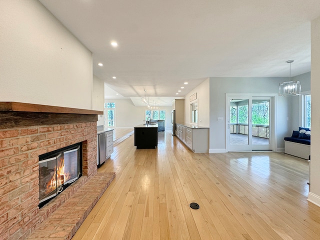 unfurnished living room with sink, an inviting chandelier, light hardwood / wood-style flooring, and a fireplace