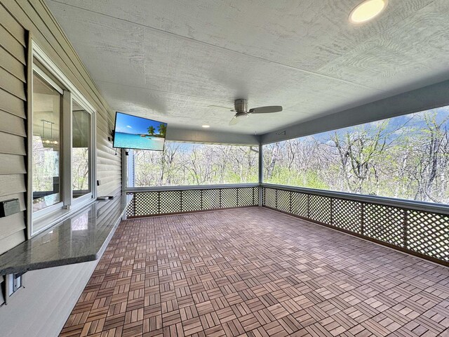 unfurnished sunroom featuring ceiling fan and a healthy amount of sunlight