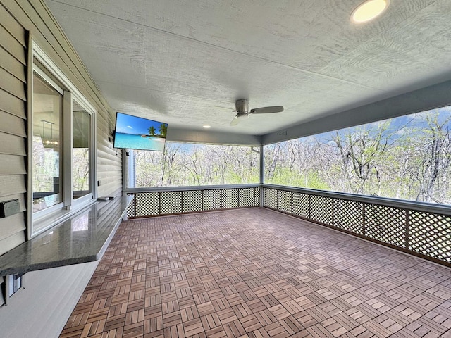 unfurnished sunroom with ceiling fan