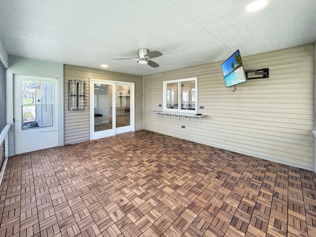 unfurnished sunroom featuring ceiling fan