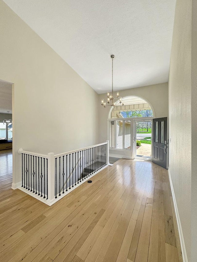 unfurnished dining area with hardwood / wood-style flooring, a towering ceiling, a textured ceiling, and a chandelier