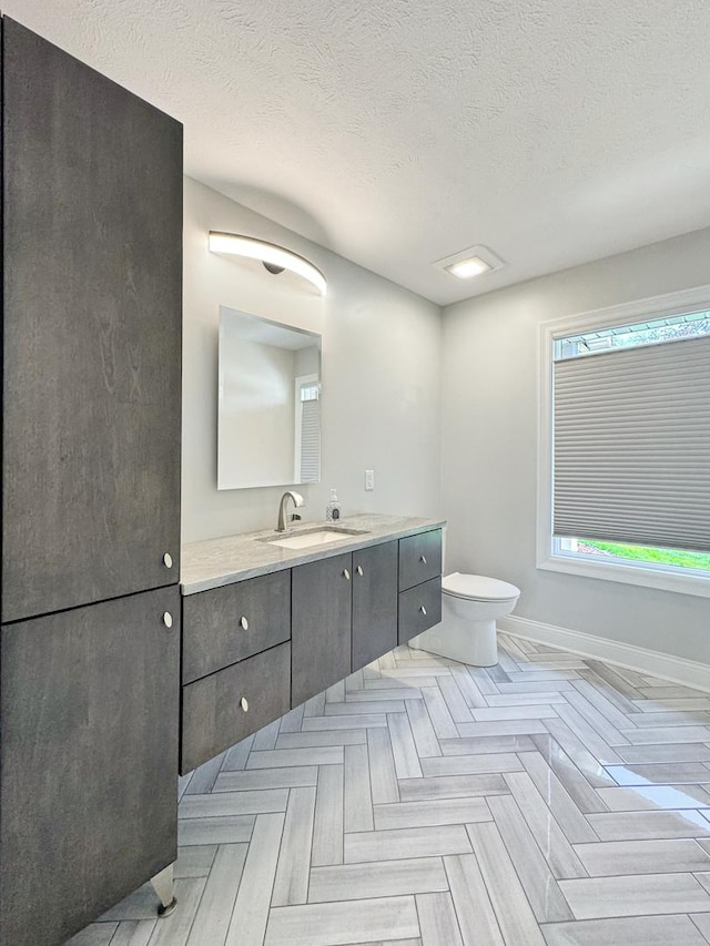 bathroom featuring vanity, parquet flooring, a textured ceiling, and toilet