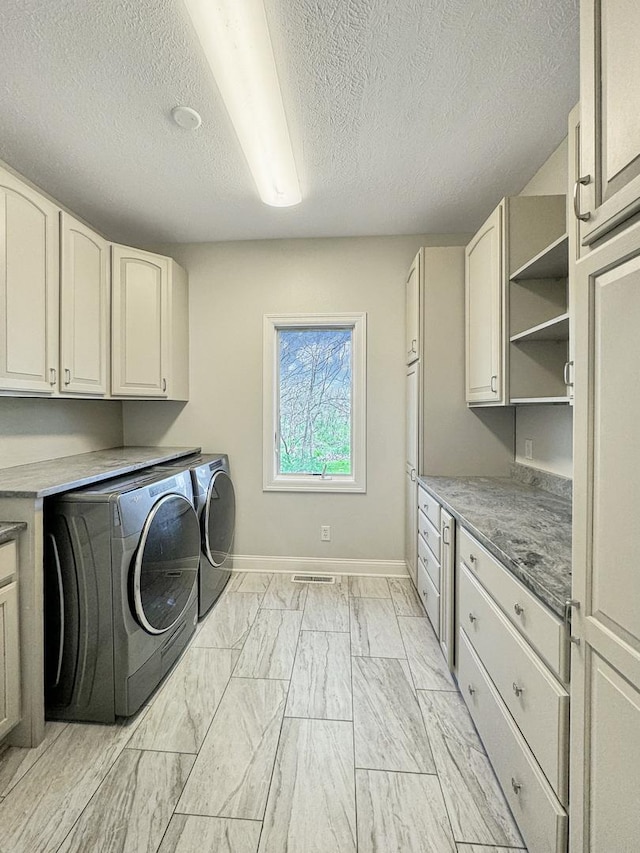 clothes washing area featuring washer and clothes dryer and cabinets