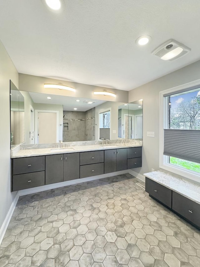 bathroom featuring vanity, a tile shower, and a wealth of natural light