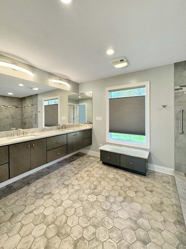 bathroom featuring a wealth of natural light, an enclosed shower, dual bowl vanity, and tile patterned floors