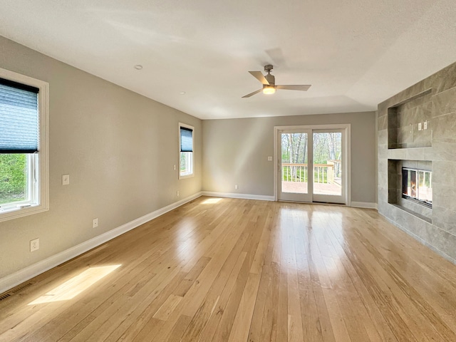 unfurnished living room featuring light hardwood / wood-style floors, a wealth of natural light, and a tiled fireplace