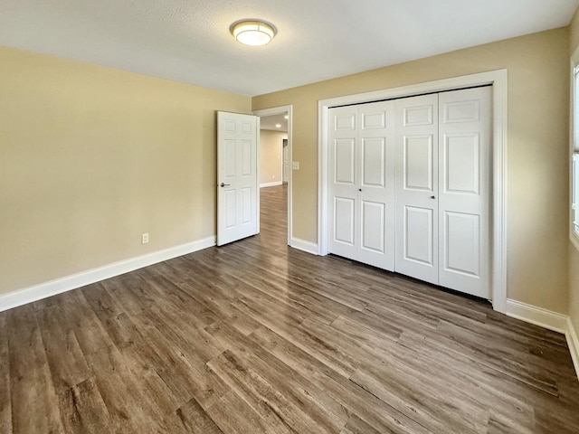 unfurnished bedroom with dark hardwood / wood-style flooring and a closet