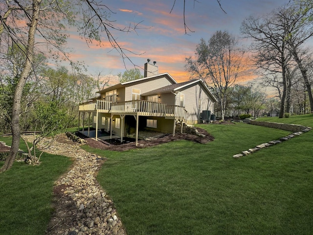 back house at dusk featuring a lawn, central air condition unit, and a deck