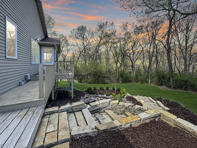 yard at dusk featuring a wooden deck