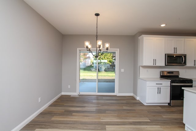 kitchen with a notable chandelier, appliances with stainless steel finishes, white cabinetry, and light hardwood / wood-style flooring