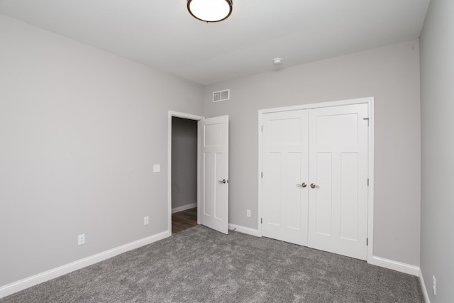 unfurnished bedroom with a closet and dark carpet