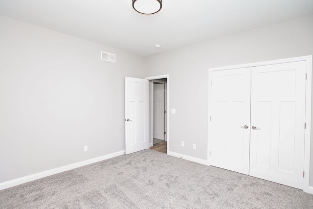 unfurnished bedroom featuring light colored carpet and a closet