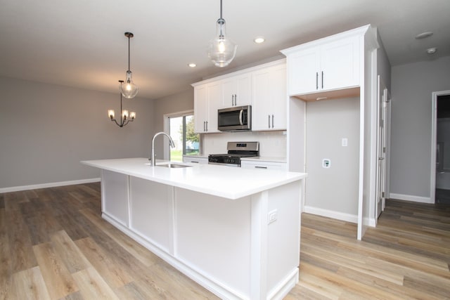 kitchen with appliances with stainless steel finishes, a kitchen island with sink, light wood-type flooring, and sink