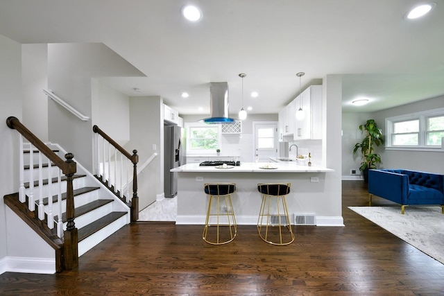 kitchen featuring white cabinetry, dark wood-type flooring, a wealth of natural light, stainless steel refrigerator with ice dispenser, and exhaust hood