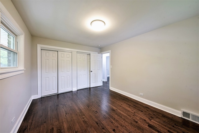 unfurnished bedroom with two closets and dark hardwood / wood-style floors