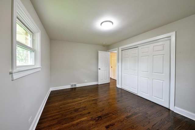 unfurnished bedroom with dark hardwood / wood-style flooring and a closet