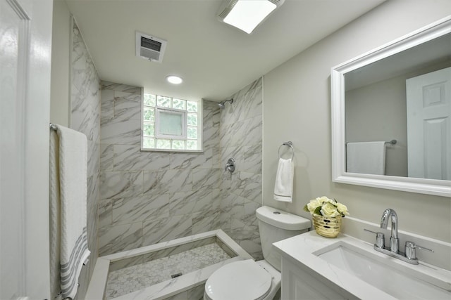 bathroom featuring toilet, a tile shower, and vanity