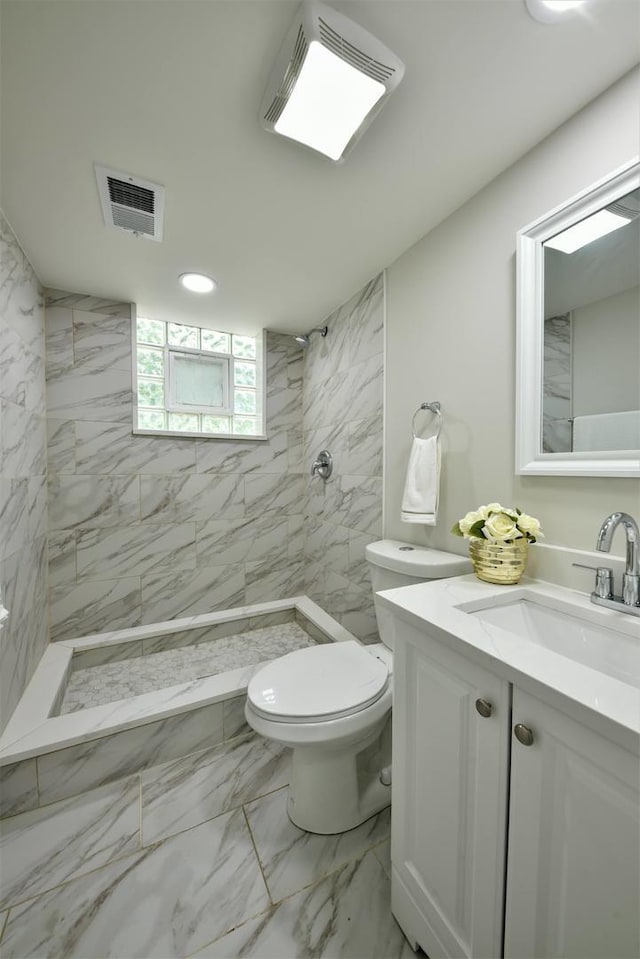 bathroom with toilet, a tile shower, vanity, and tile flooring