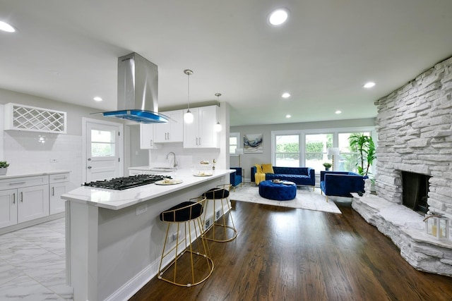 kitchen with backsplash, white cabinets, pendant lighting, and island exhaust hood