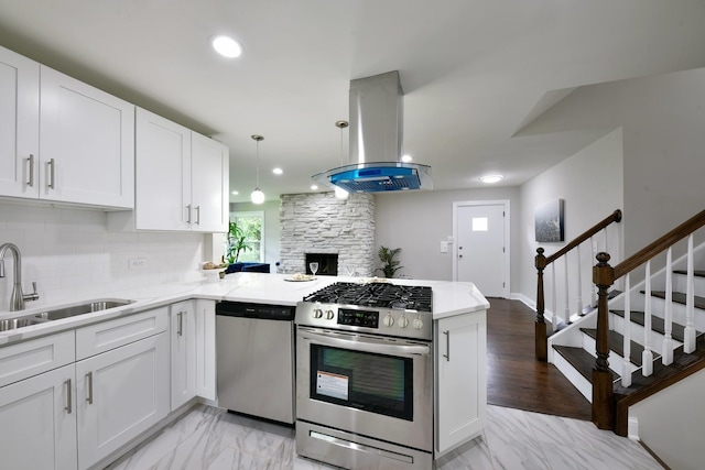 kitchen featuring kitchen peninsula, white cabinetry, stainless steel appliances, island range hood, and tasteful backsplash