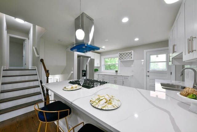 kitchen featuring appliances with stainless steel finishes, backsplash, island exhaust hood, and white cabinets