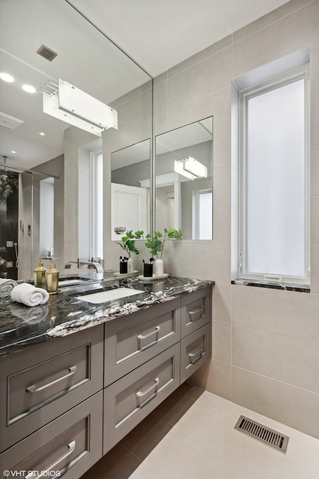 bathroom with tile flooring, tile walls, and vanity