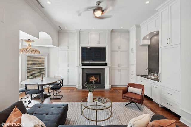 living room with ceiling fan, sink, hardwood / wood-style flooring, and crown molding