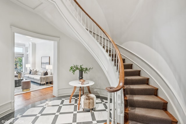 stairway with ornamental molding and hardwood / wood-style floors