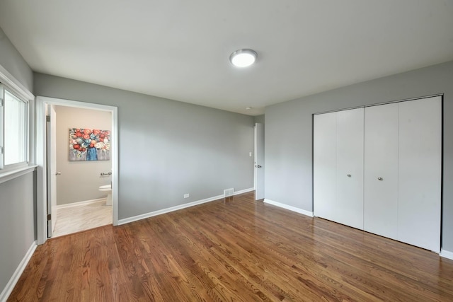 unfurnished bedroom featuring connected bathroom, a closet, and dark hardwood / wood-style floors