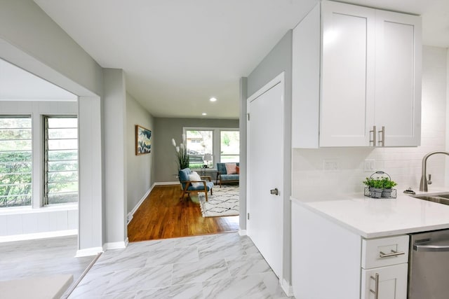 kitchen with light tile flooring, tasteful backsplash, dishwasher, sink, and white cabinets