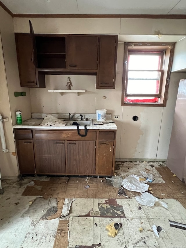 kitchen with ornamental molding, sink, and dark brown cabinetry