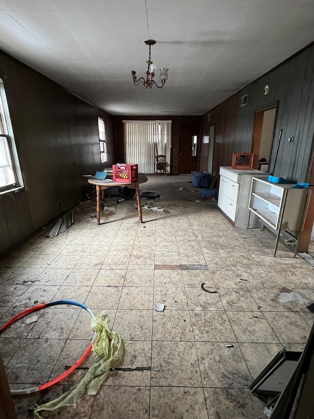 misc room with light tile floors, wooden walls, and a chandelier