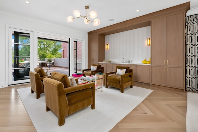 living room featuring light parquet flooring, ornamental molding, sink, and a chandelier