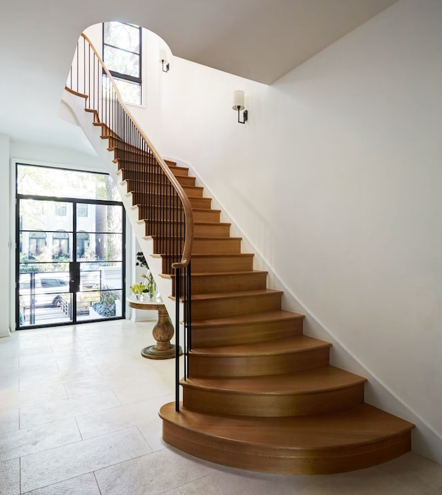 stairs with light tile floors and french doors