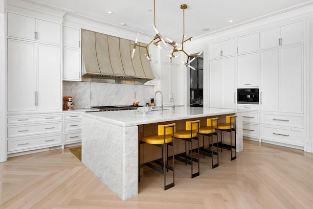 kitchen with pendant lighting, light parquet floors, a center island with sink, and a breakfast bar area