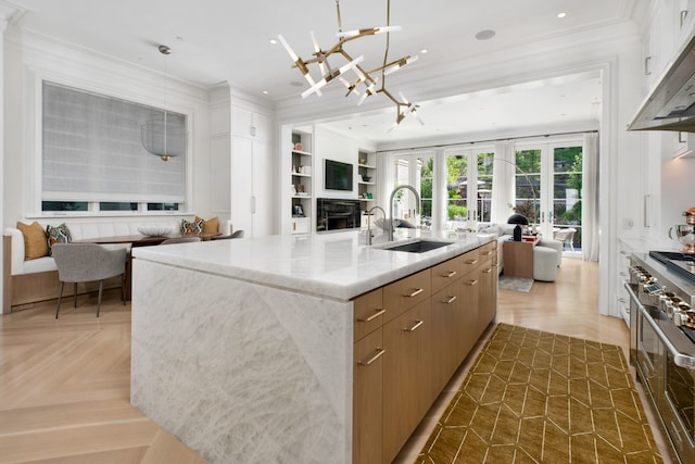 kitchen featuring light stone countertops, pendant lighting, parquet floors, and a kitchen island with sink