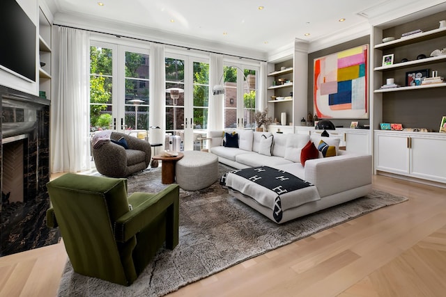 living room featuring built in features, a wealth of natural light, a premium fireplace, and french doors