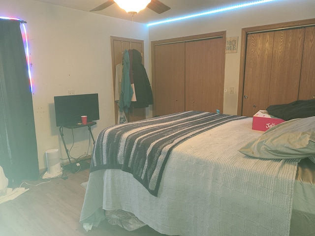 bedroom with multiple closets, light hardwood / wood-style floors, and ceiling fan