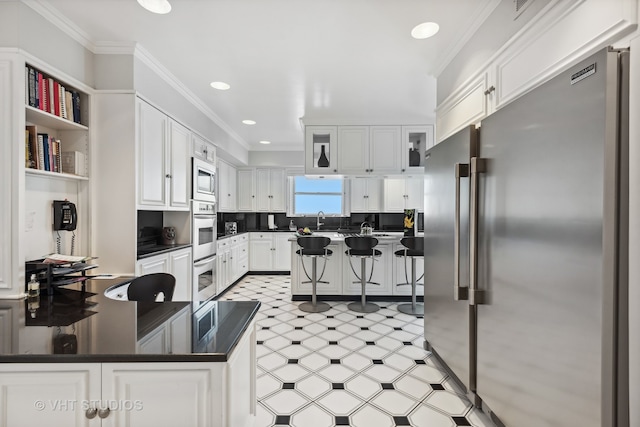 kitchen featuring white cabinets, tasteful backsplash, appliances with stainless steel finishes, and crown molding