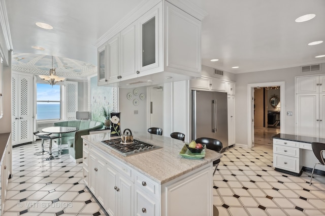 kitchen with a chandelier, a water view, appliances with stainless steel finishes, and white cabinetry