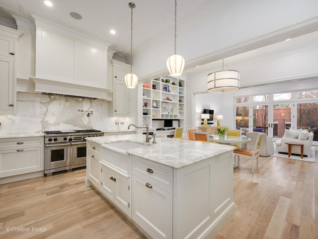 kitchen with tasteful backsplash, double oven range, light stone counters, and light hardwood / wood-style flooring