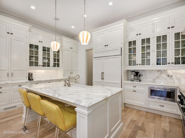 kitchen featuring decorative light fixtures, light hardwood / wood-style flooring, tasteful backsplash, a kitchen island, and built in appliances