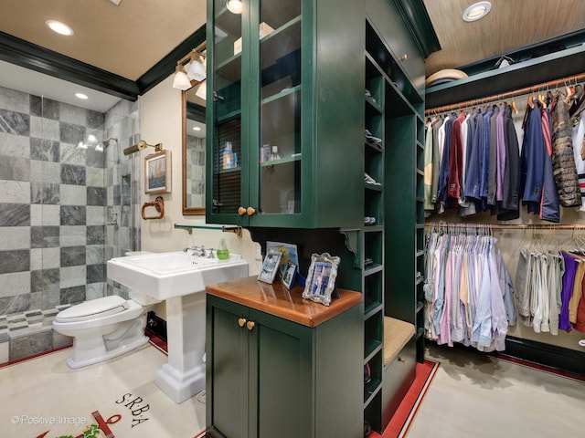 bathroom featuring tiled shower, sink, toilet, and tile walls