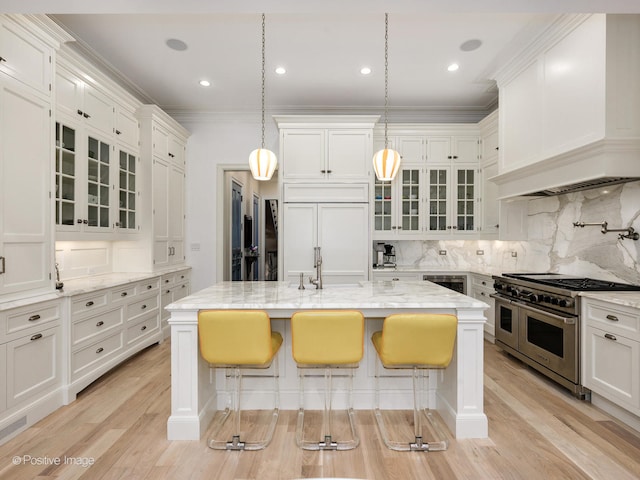 kitchen with backsplash, a breakfast bar, white cabinetry, and premium appliances