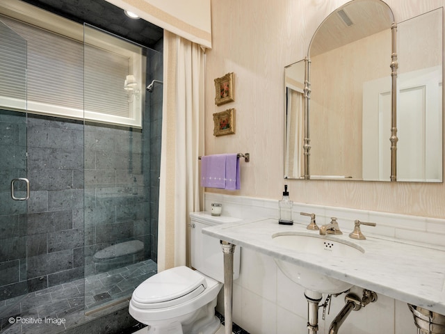 bathroom featuring sink, toilet, and a shower with door