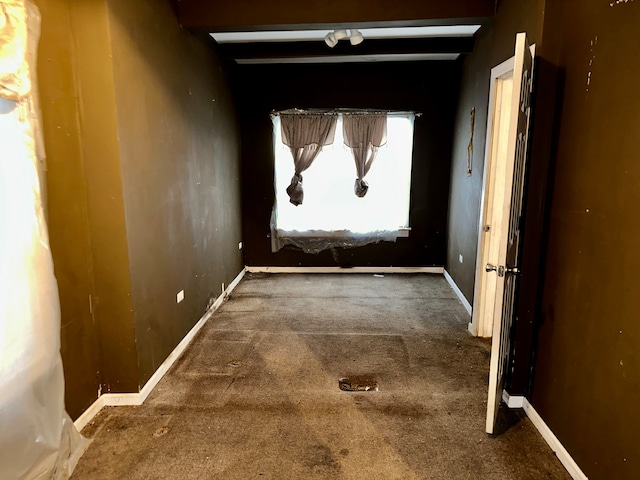 corridor featuring dark colored carpet and beamed ceiling