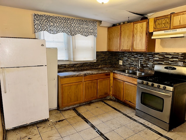 kitchen featuring stainless steel gas range oven, light tile floors, white fridge, tasteful backsplash, and sink